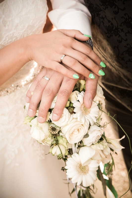 Hochzeitspaar mit weißem Brautstrauß und Ringen
